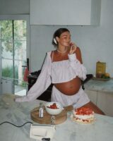 Mulher jovem, grávida de pele clara, Ela usa conjunto com listras.