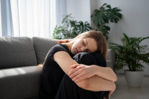Mulher agachada com os braços ao redor das pernas.