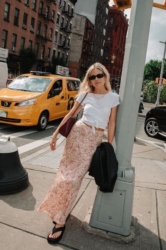 Mulher jovem e magra com saia midi, blusa e sandália flatform preta