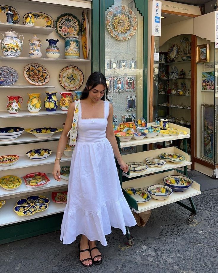 Mulher jovem e magra com pele clara. Ela usa vestido longo com calças largas.