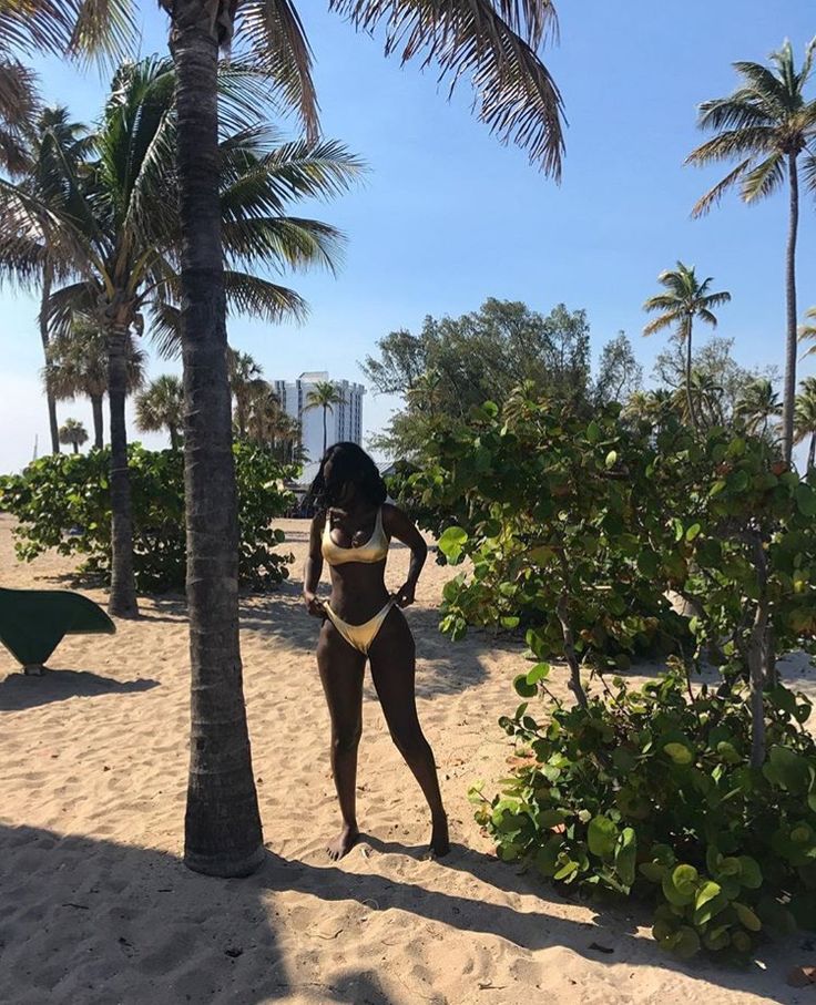 Mulher jovem, magra e negra, usando biquíni de frente única na cor dourado.