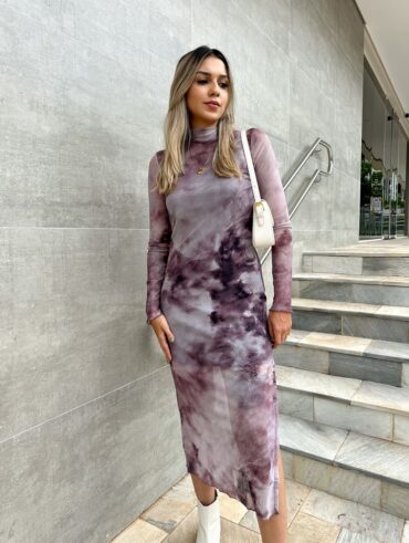 Mulher jovem, branca, magra e loira de cabelo médio, usando vestido de segunda pele em tule estampado com bolsa de ombro na cor branca.