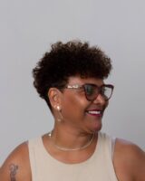Mulher negra com cabelo bixie, crespo e castanho