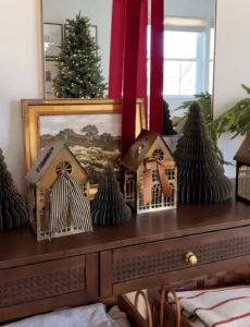 Aparador com decoração natalina, com casas enfeitadas com laços e árvore de Natal