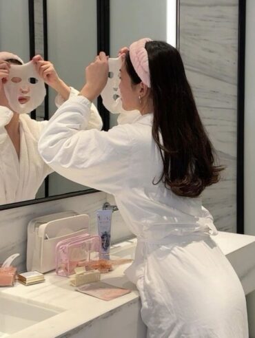 Mulher de pele branca, com cabelo escuro fazendo skincare