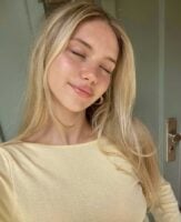 Mulher de pele branca, com blusa amarelo-manteiga e cabelo loiro solto