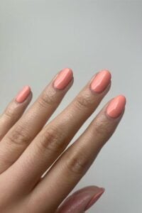 Mão de pele clara com unha amendoada pêssego