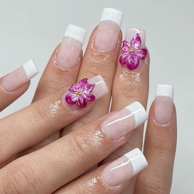 Mãos de pele branca, com unha quadrada com francesinha e charm de flor 