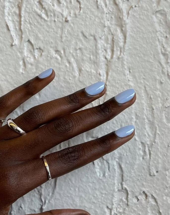 Mão de pele preta, com acessórios em prata e unha amendoada azul Tiffany 