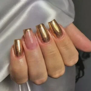 Mão de pele branca, com unha quadrada e esmalte dourado metalizado