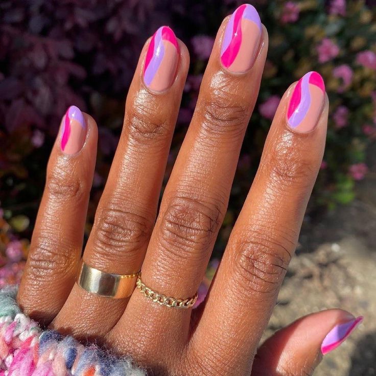 Mão de pele preta, com acessórios em dourado e unha amendoada com francesinha lilás e rosa