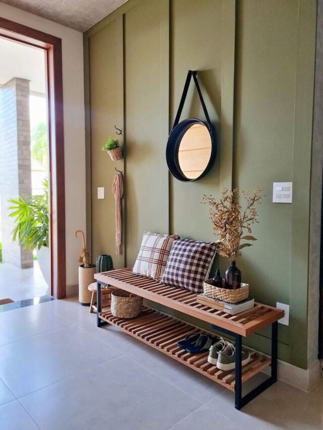 Hall de entrada com parede verde, banco com almofadas e espelho Adnet