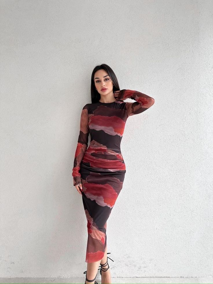 Mulher jovem, magra e branca, com cabelo liso e moreno, usando vestido segunda pele estampado com sandália.
