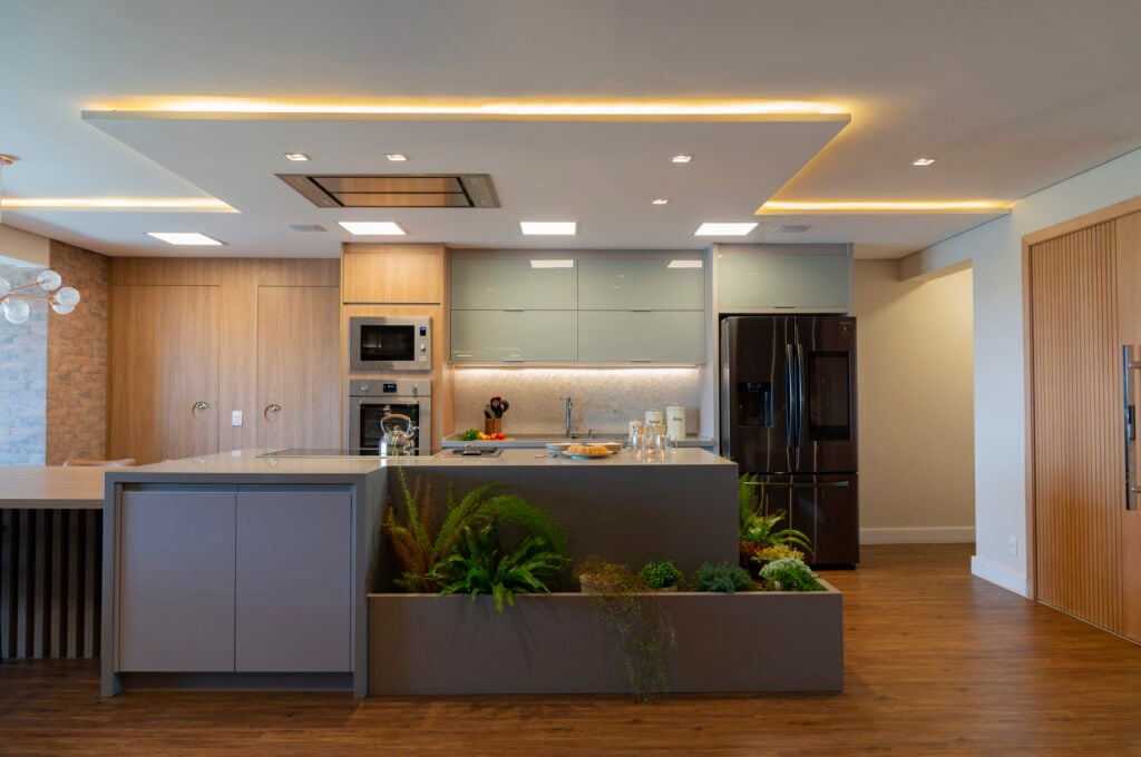 Cozinha em tons amadeirados, cinza e luz de led no teto com gesso
