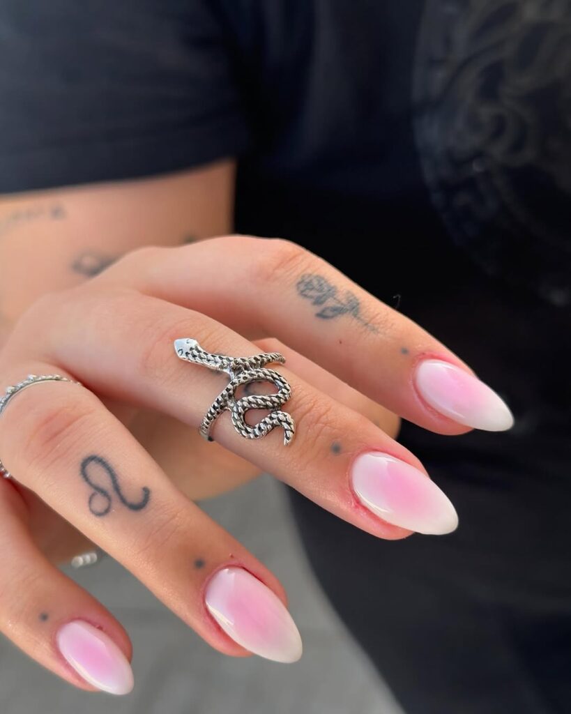 Mão de pele branca, com unha em formato amendoado com nail art de aura nails rosa