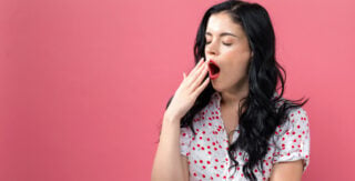 Mulher bocejando em fundo rosa