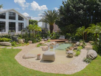 Casa em estilo farm house, com praia artificial no jardim, com pedras e deck de madeira