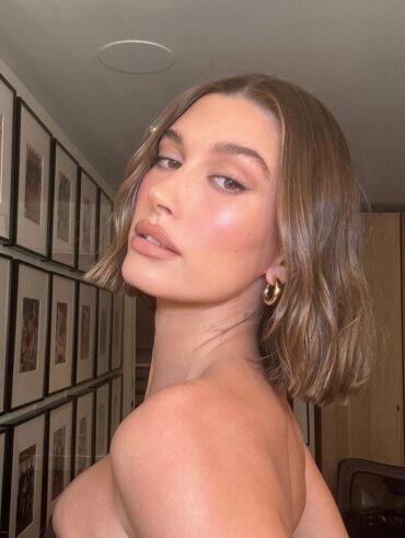 Hailey Bieber com acessórios em dourado e cabelo castanho com corte bob