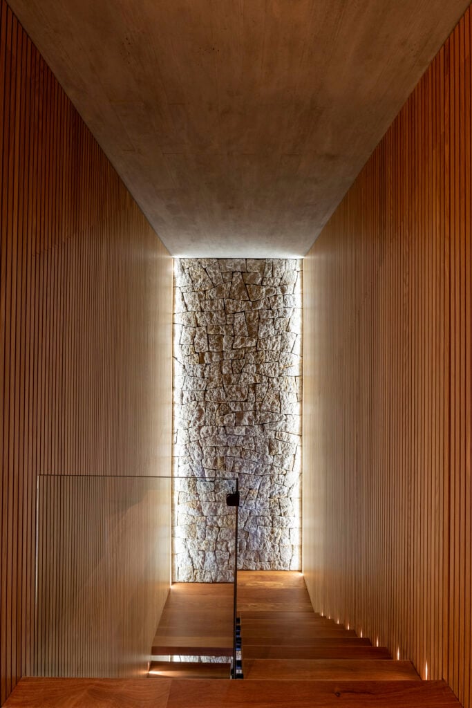 Escada com pedras na parede e iluminação sob medida