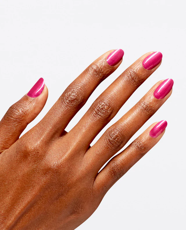 Mão de pele preta, com unha amendoada pintada com o esmalte rosa-choque com brilho Glinda The Good, da OPI