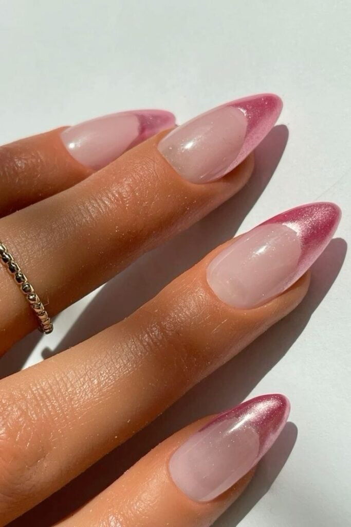 Mão de pele clara, com anéis em dourado e unha amendoada com francesinha metalizada