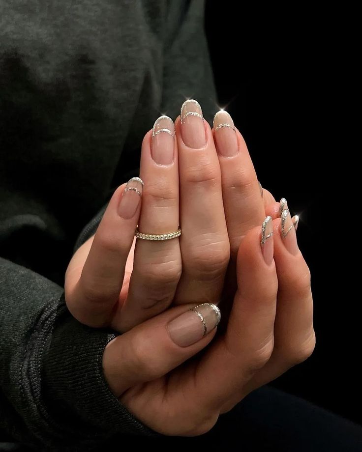 Mãos de pele branca, com anel de brilhante e unha amendoada natural com francesinha vazada de glitter