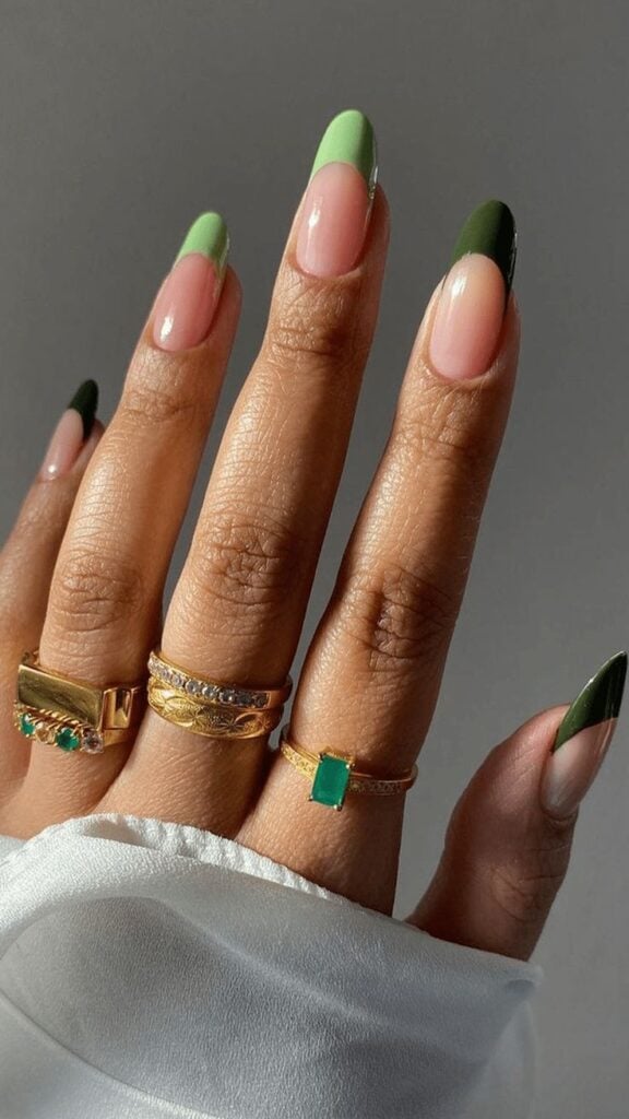 Mão de pele clara, com anéis em dourado e unha amendoada com francesinha verde degradê