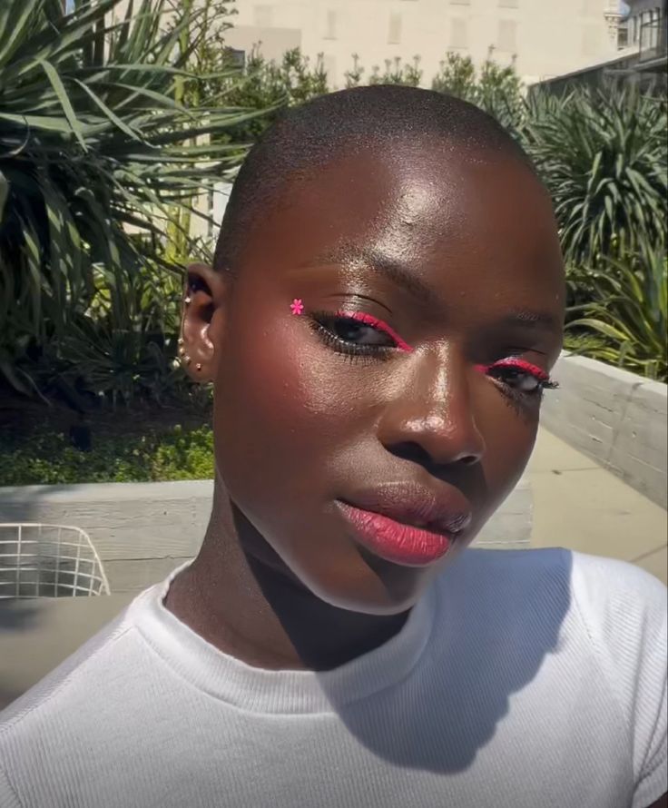 Mulher de pele preta, com blusa branca e maquiagem com delineado gráfico rosa 