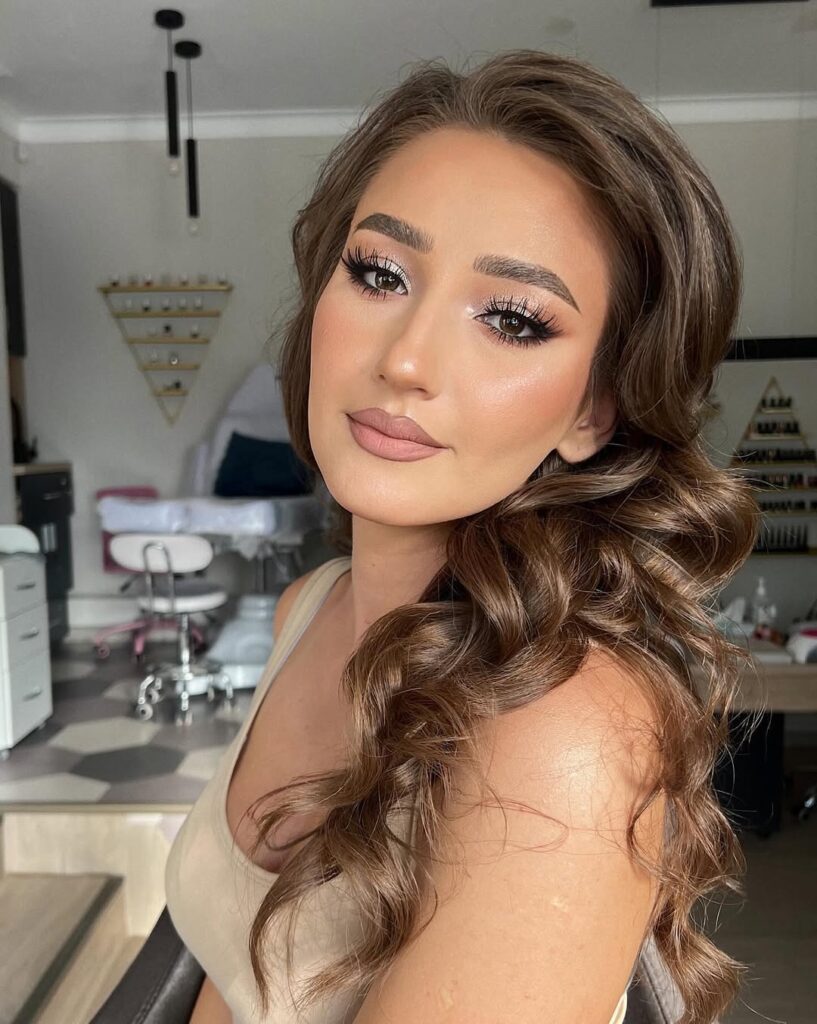 Mulher de pele clara, com cabelo castanho e maquiagem com sombra prata
