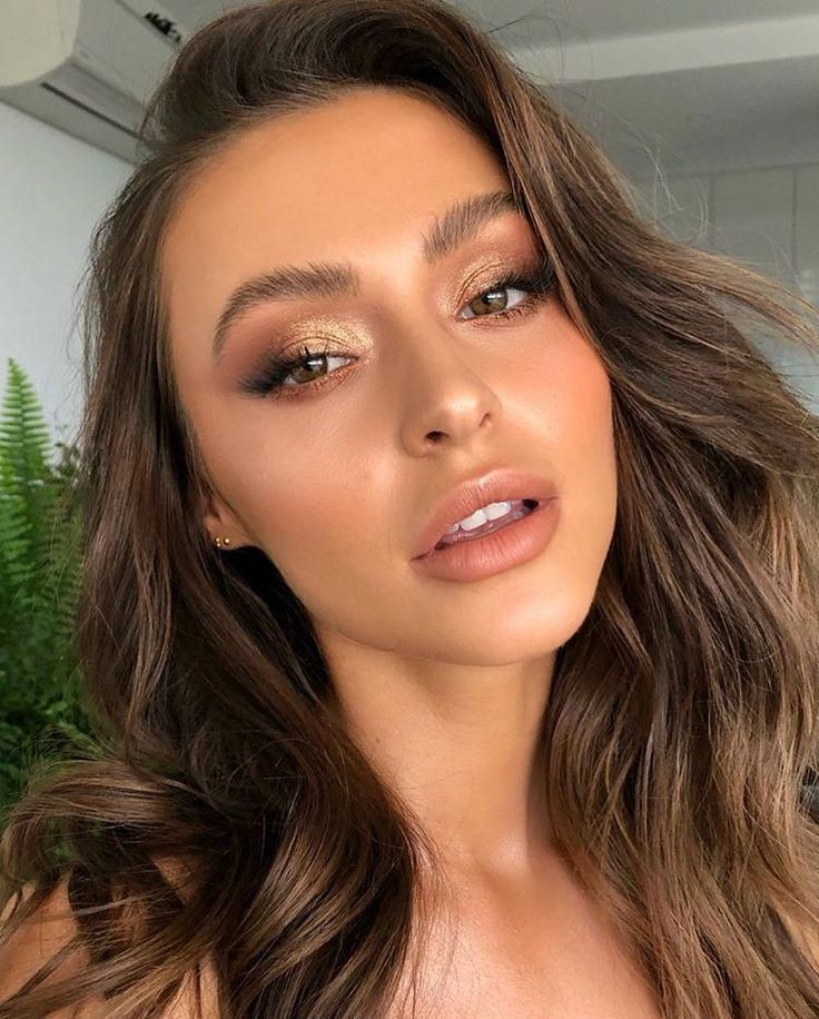 Mulher de pele clara, com cabelo escuro e maquiagem dourada 