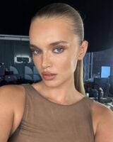 Mulher de pele clara, com cabelo loiro preso, blusa marrom e maquiagem em tons de marrom