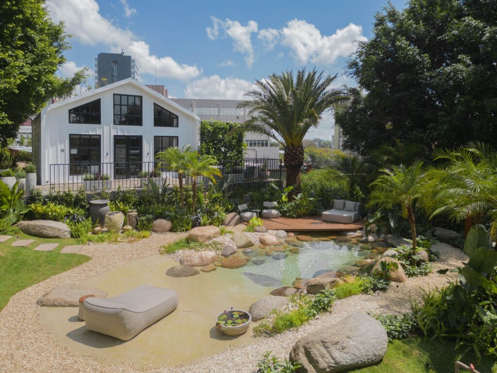Casa em estilo farm house, com praia artificial no jardim, com pedras e deck de madeira