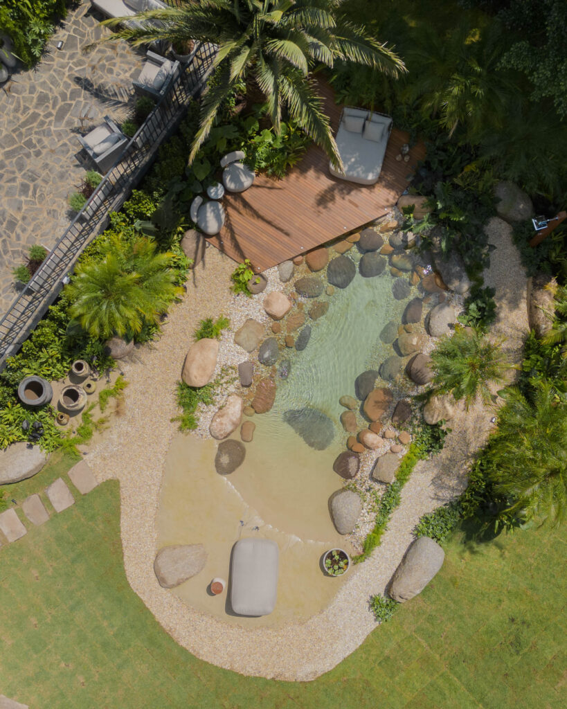 Praia artificial no jardim, com pedras e deck de madeira