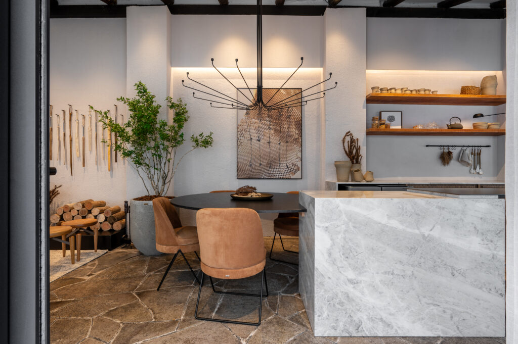 Ambiente com mesa preta em metal, cadeiras aveludadas em marrom