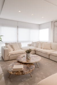 Sala de estar com sofás neutros, mesas de centro