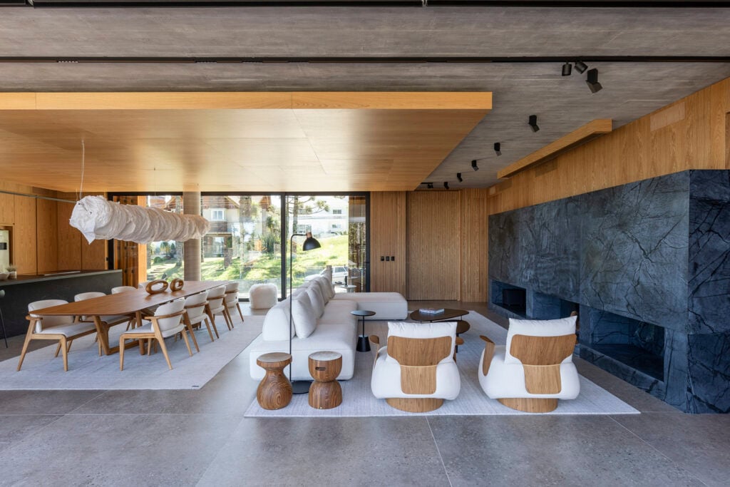 Sala de estar com sofá branco e grande e poltronas, com lareira de pedra
