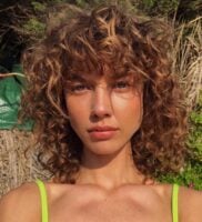 Mulher de pele clara, com cabelo cacheado com o corte shaggy