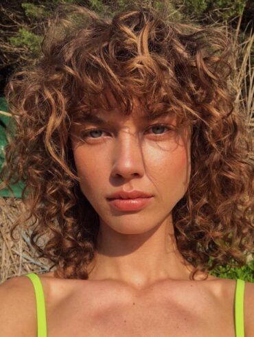 Mulher de pele clara, com cabelo cacheado com o corte shaggy