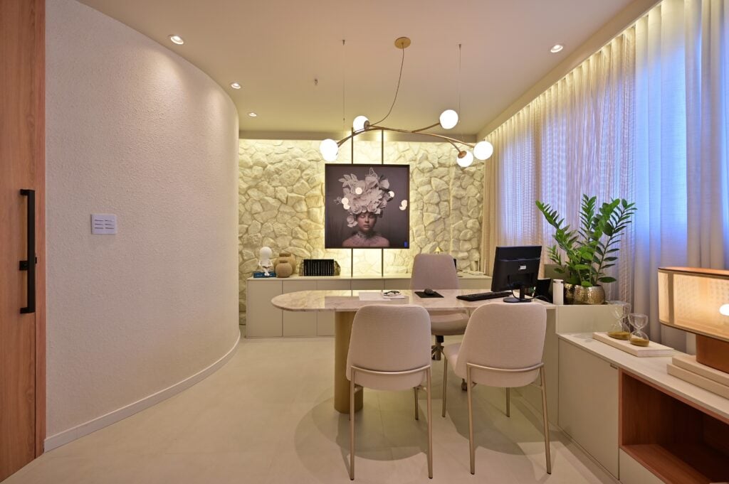 Sala de atendimento com parede curva, revestimento de pedras, elementos em cores neutras
