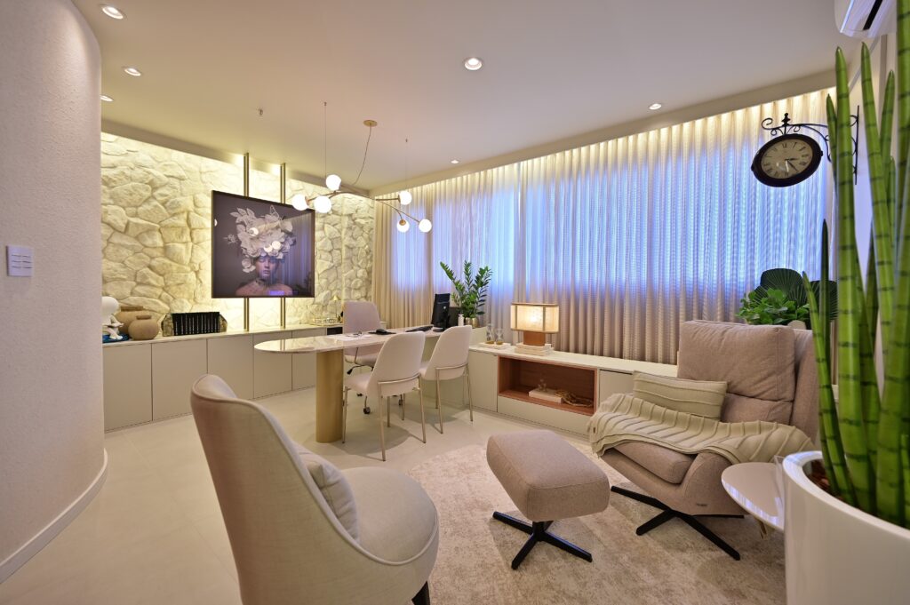 Sala de atendimento com poltronas e cortinas neutras, com parede revestida de pedra