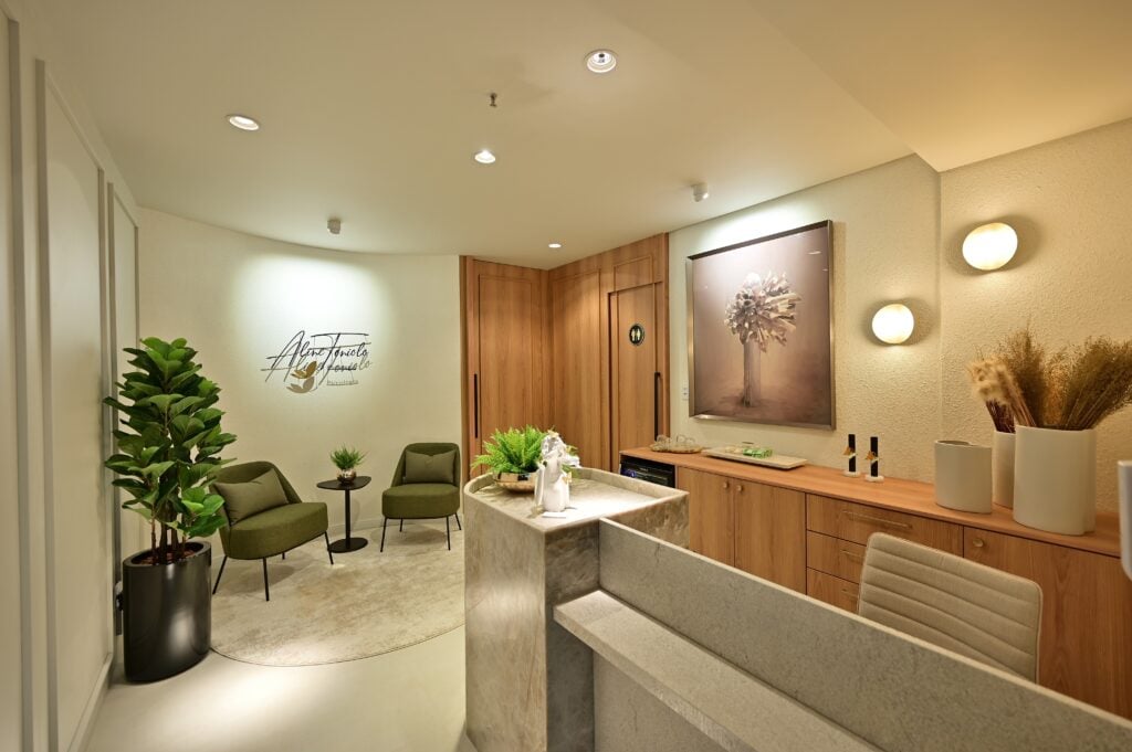 Sala de recepção com poltronas verde-oliva, móveis em madeira e paredes neutras
