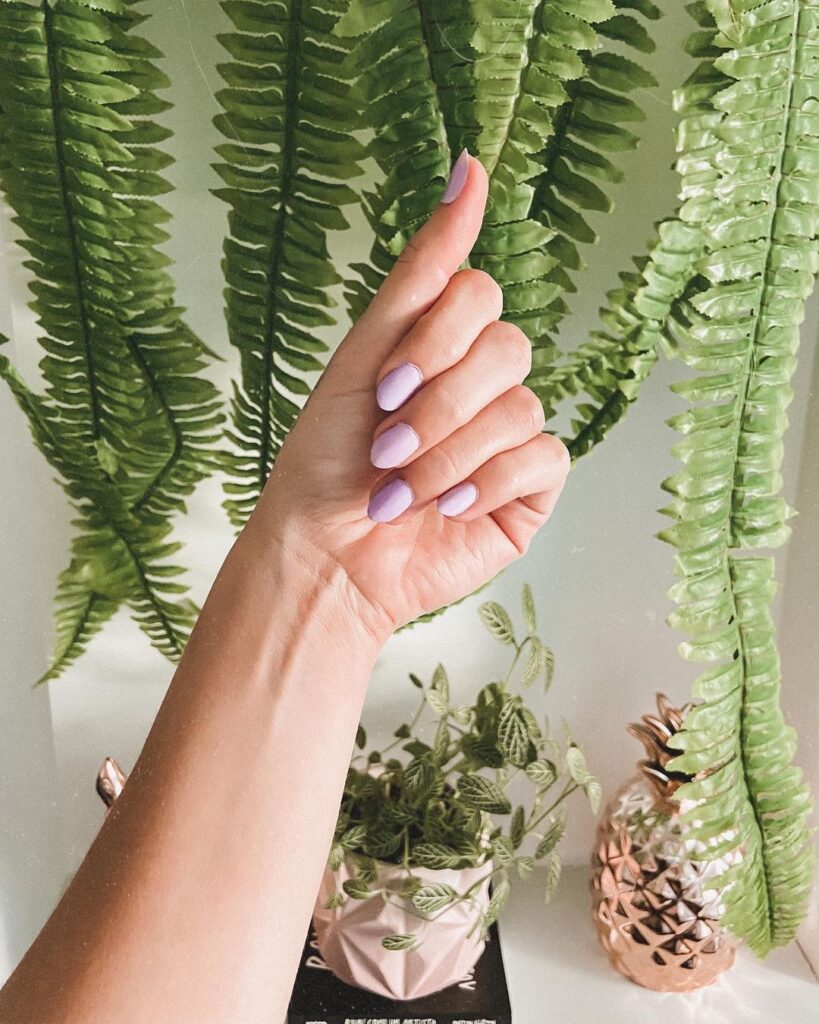 Mão de pele clara com unha amendoada lavanda
