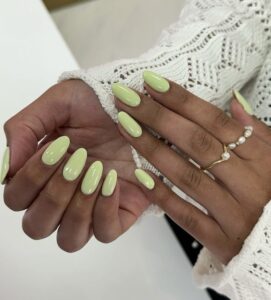 Mãos de pele negra, com anéis em dourado e unha amendoada verde-pistache
