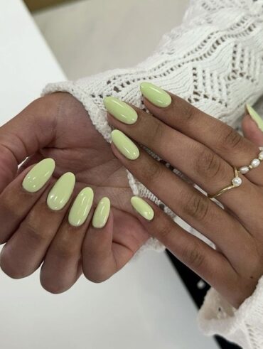 Mãos de pele negra, com anéis em dourado e unha amendoada verde-pistache