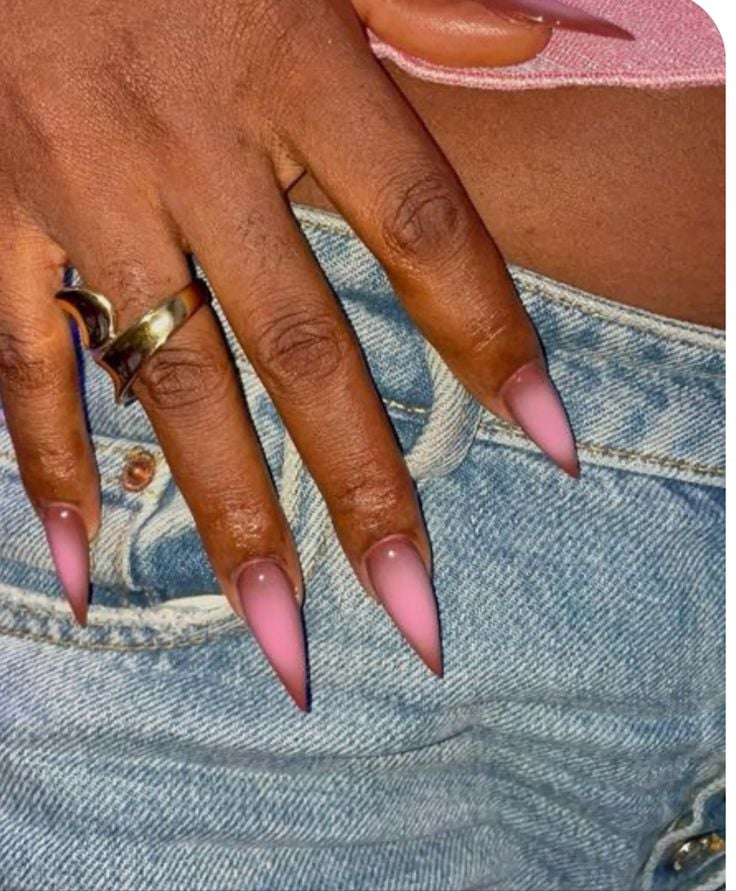 Mão de pele preta, com anel em dourado e unha stiletto com design aura