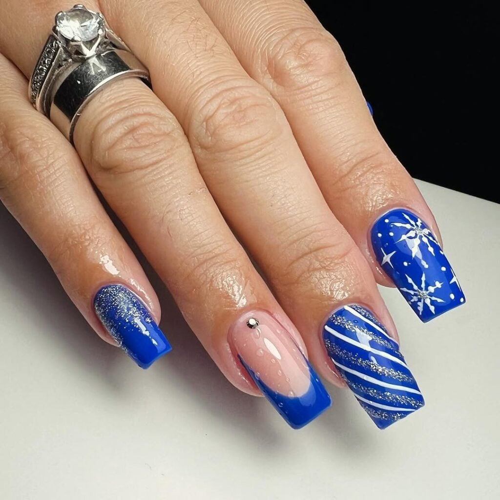 Mão de pele clara, com anéis em prata, e unha quadrada azul com brilho 