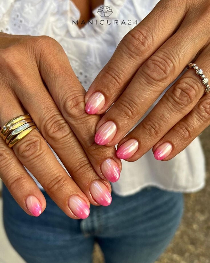Mão de pele clara, com anéis em dourado e prata e unha amendoada baby boomer rosa