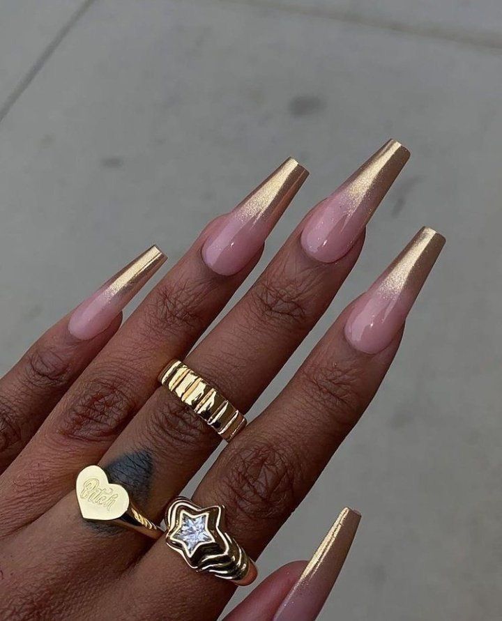 Mão de pele preta, com anéis em dourado e unha coffin ombré dourada