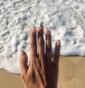 Mão de pele preta, com unha amendoada com linhas fluidas em azul