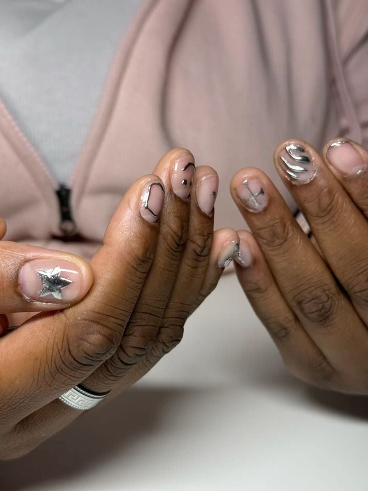 Mãos de pele preta, com unha curtinha com decoração prata metalizado